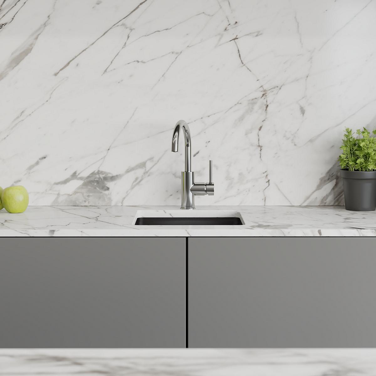 Chrome single-hole bar faucet with lever handle installed above rectangular undermount sink on marble countertop.