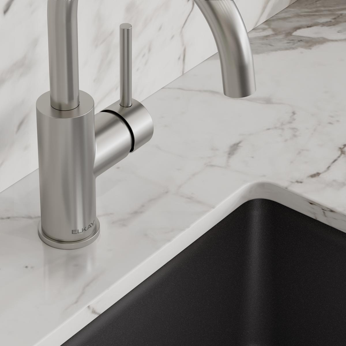 Lustrous steel bar faucet with single lever handle mounted on marble countertop above black sink.