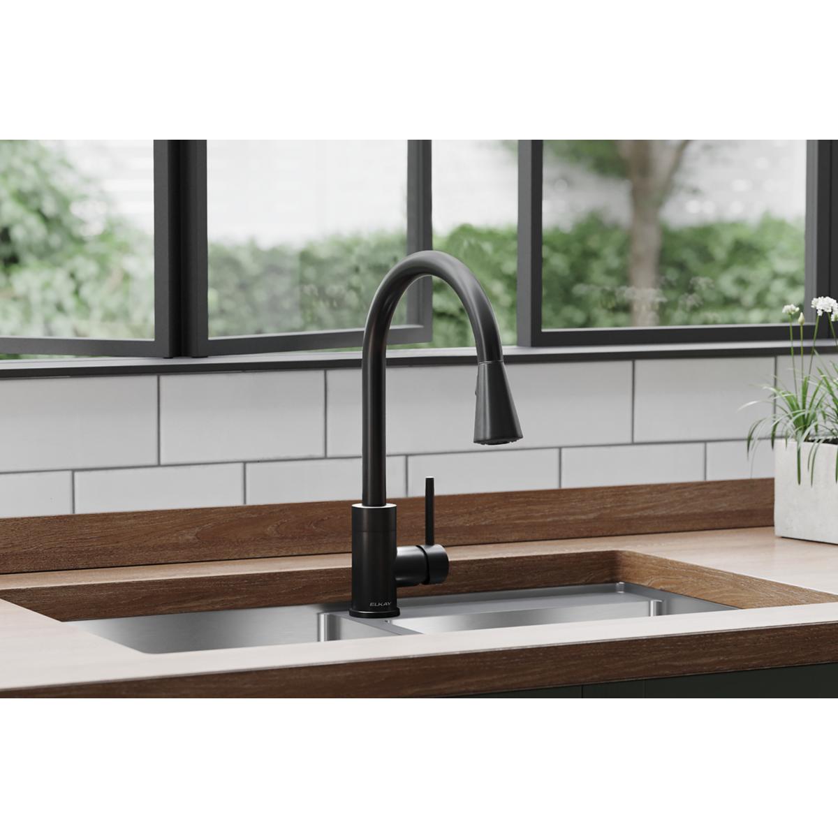 Black stainless steel kitchen faucet with curved spout and forward lever handle installed in sink counter.