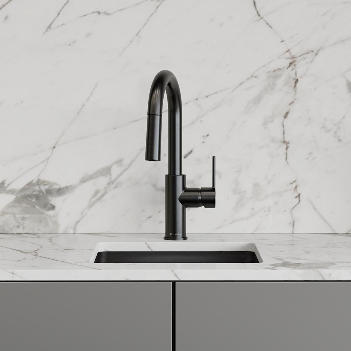 Black stainless steel single-hole bar faucet with pull-down spray and lever handle mounted on white marble countertop.