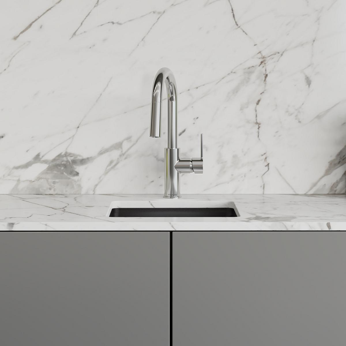 Chrome bar faucet with pull-down spray nozzle and lever handle mounted on marble countertop above sink.