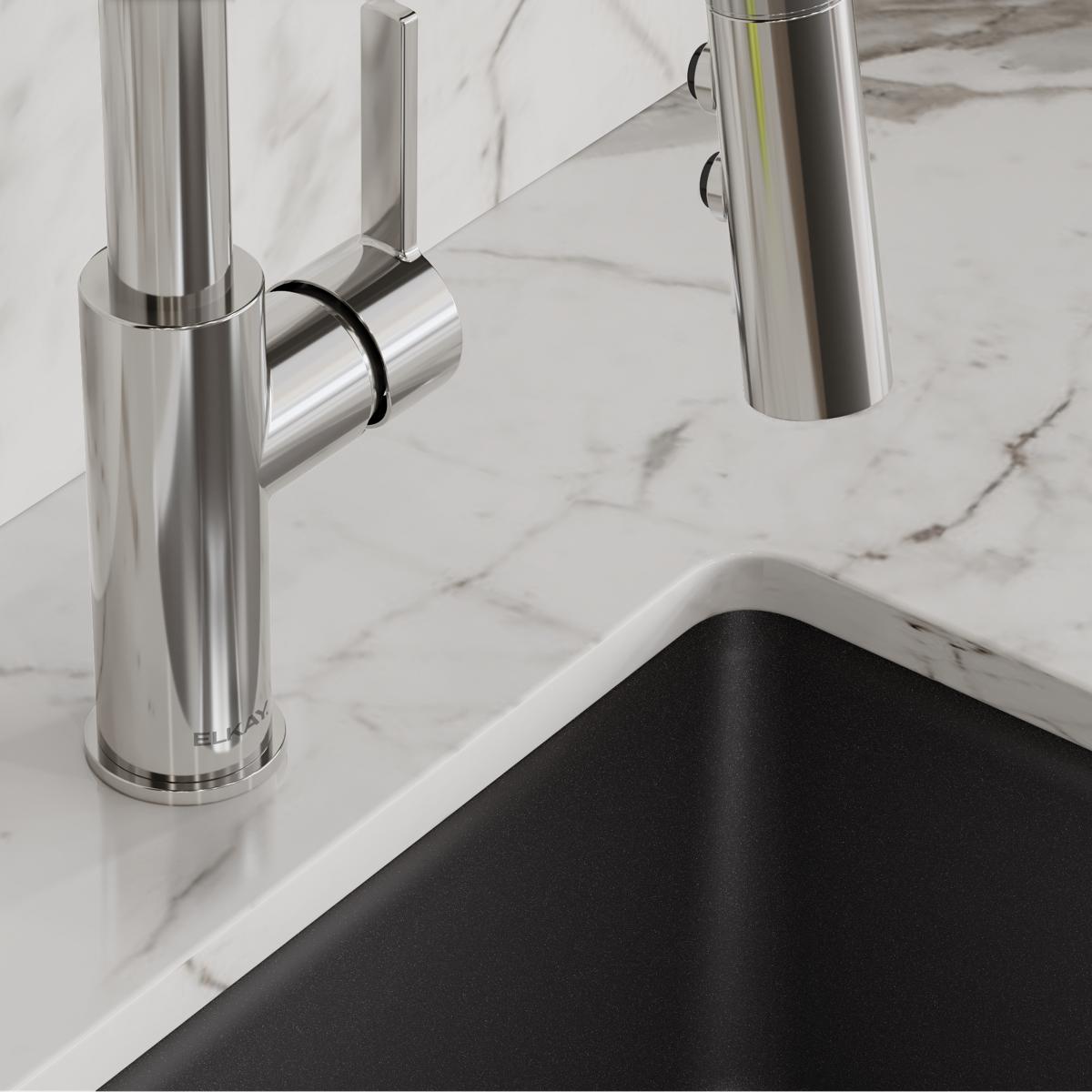 Chrome single-hole bar faucet with pull-down spray head and lever handle mounted on marble countertop above black sink.