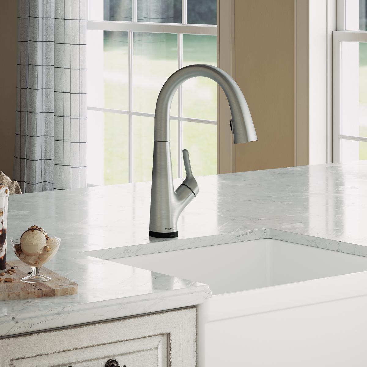 Lustrous steel kitchen faucet with curved spout and pull-down sprayer mounted above white sink.