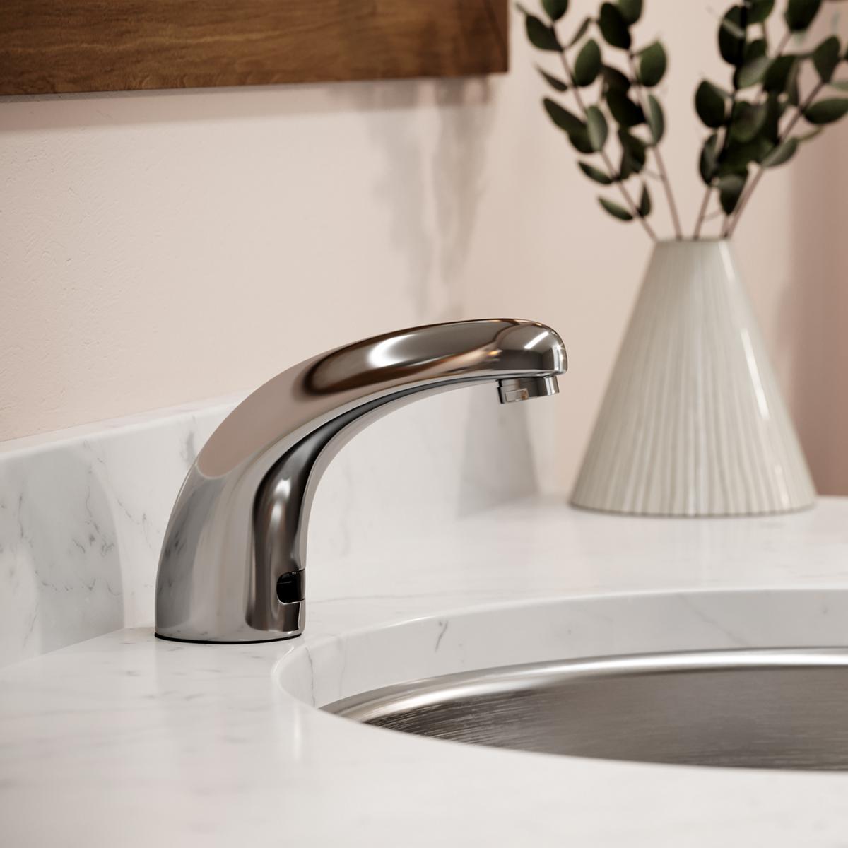 Chrome electronic deck mount faucet with curved fixed spout over white sink basin.