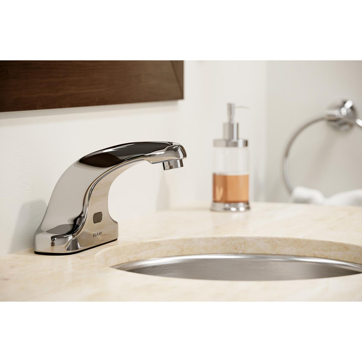 Chrome electronic deck mount faucet with fixed curved spout mounted on bathroom sink counter.
