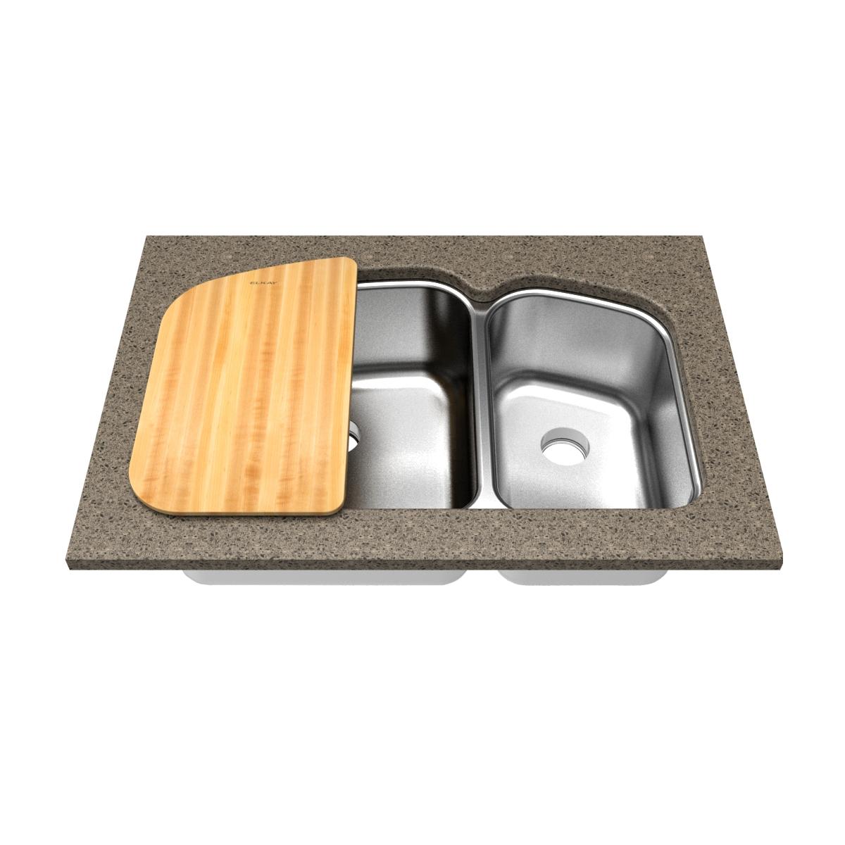 Rectangular hardwood cutting board in light wood tone positioned over a double stainless steel sink basin.