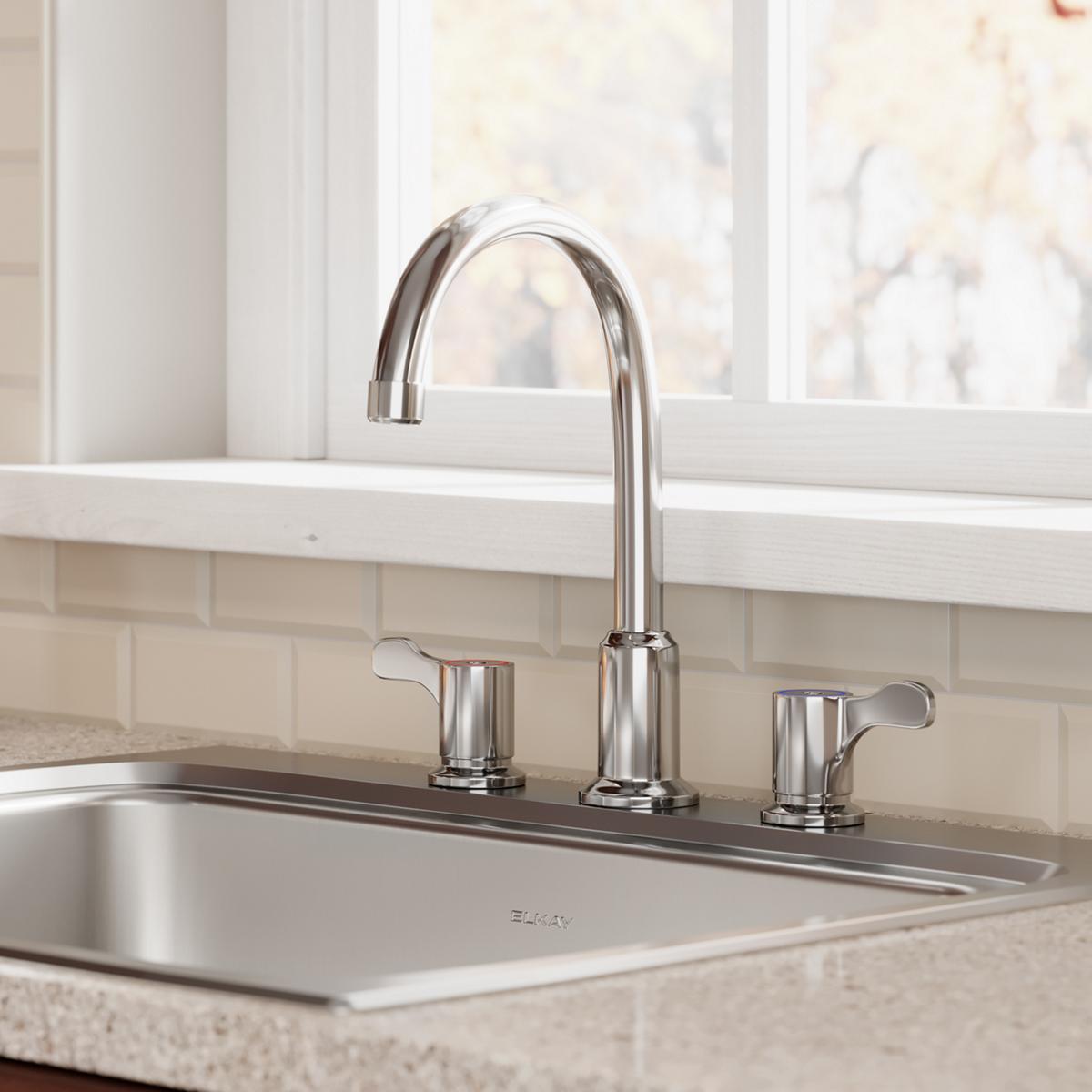 Chrome kitchen faucet with arc spout and two lever handles mounted on sink deck.