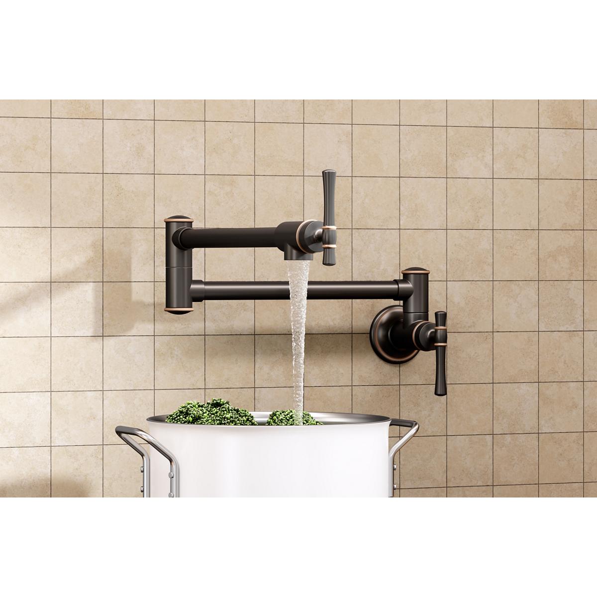 Wall-mounted oil rubbed bronze pot filler faucet with lever handles dispensing water into a white pot containing herbs.