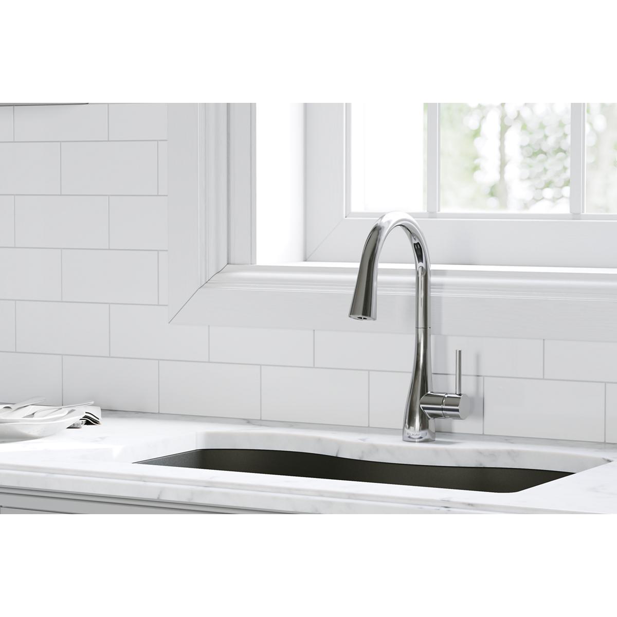 Chrome kitchen faucet with curved spout and pull-down spray head installed above rectangular sink.