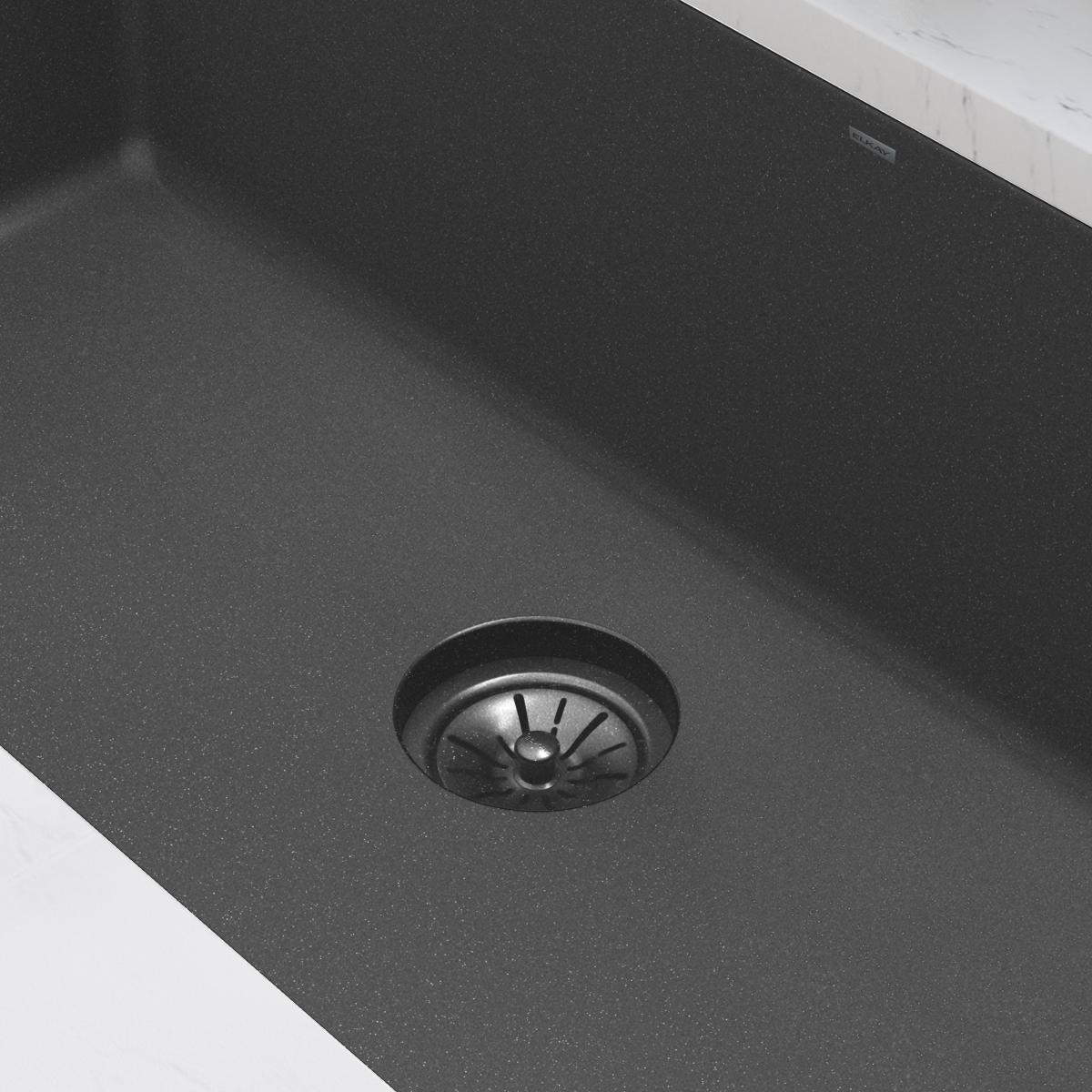 Charcoal polymer disposer flange with basket strainer installed in dark gray kitchen sink basin.