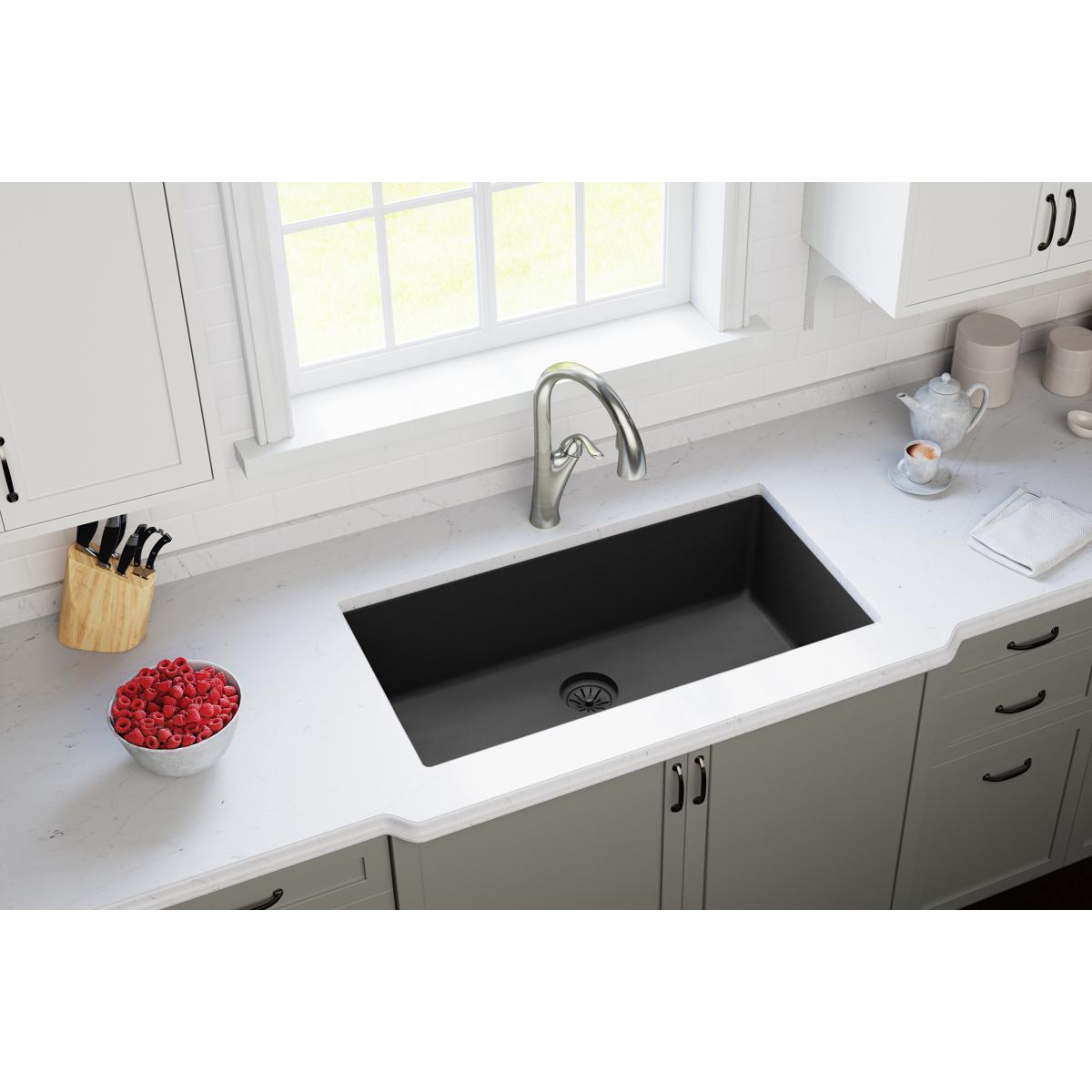 Charcoal polymer drain flange installed in black undermount kitchen sink with basket strainer visible.