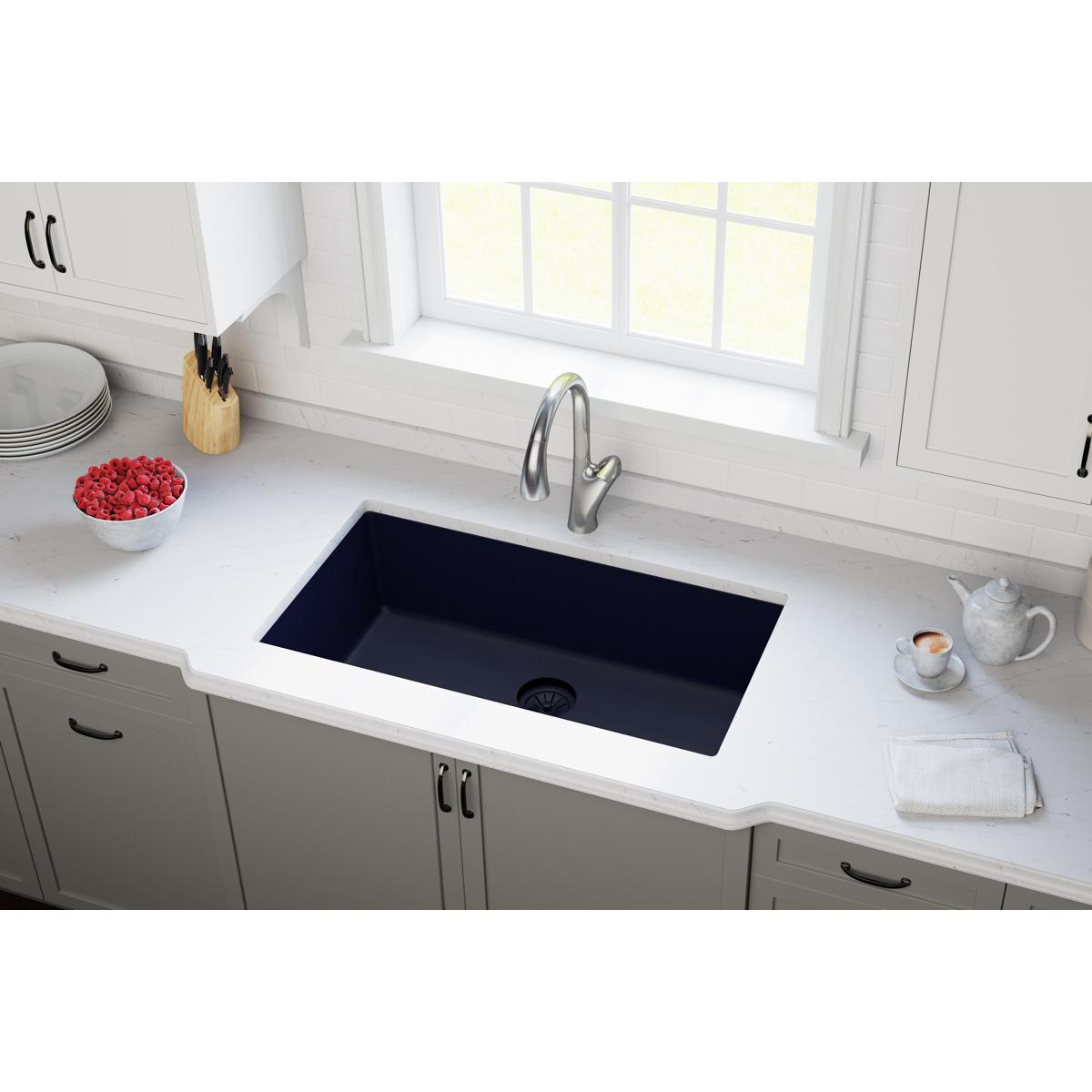 Black polymer sink drain flange with basket strainer installed in white undermount kitchen sink.