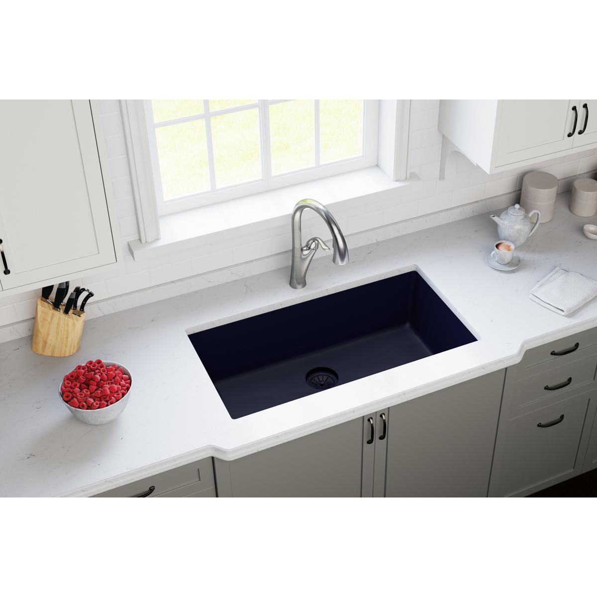 Black quartz undermount kitchen sink with drain opening visible in white countertop.