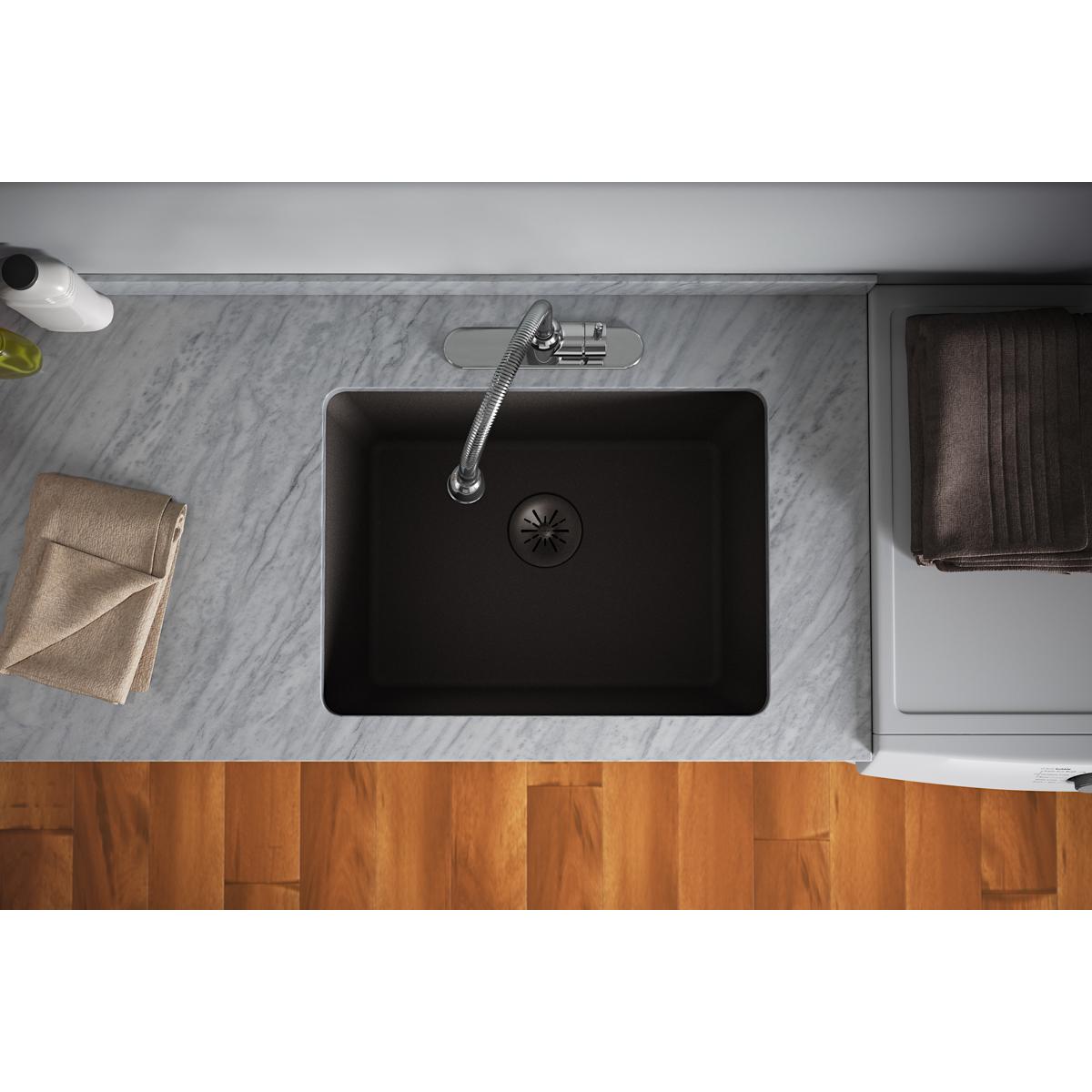 Black polymer basket strainer with drain opening visible in center of quartz sink basin.