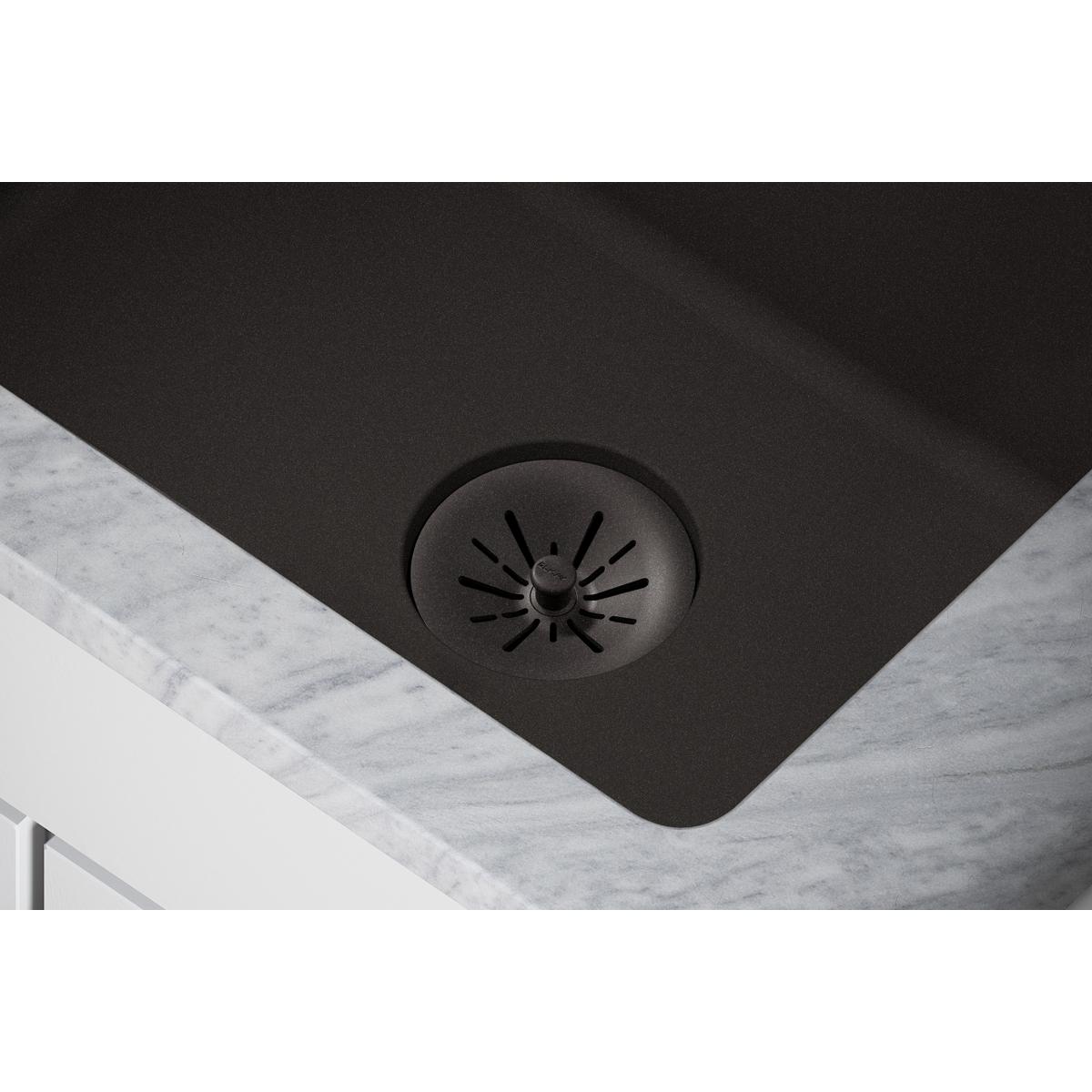 Black polymer basket strainer with radiating slots installed in dark sink basin.