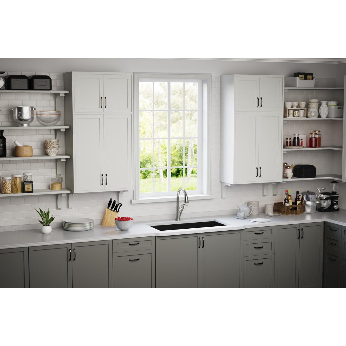 Black rectangular sink with drain strainer installed in white quartz countertop in kitchen setting.