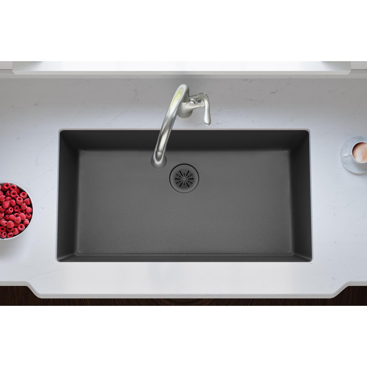 Charcoal quartz kitchen sink with removable polymer basket strainer and rubber stopper drain visible in center.