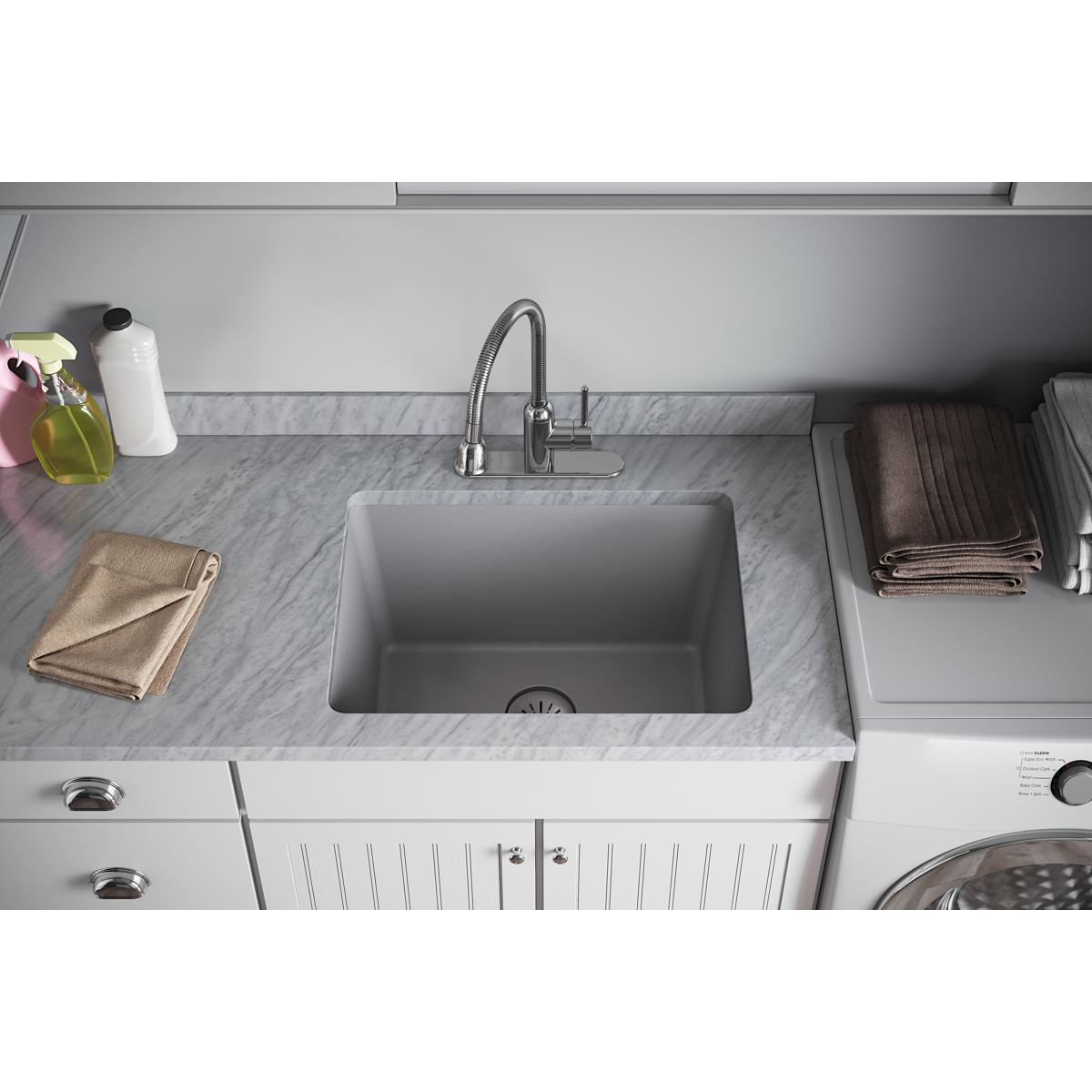 Greystone quartz sink basin with drain strainer visible at bottom center, installed in white cabinetry with marble countertop