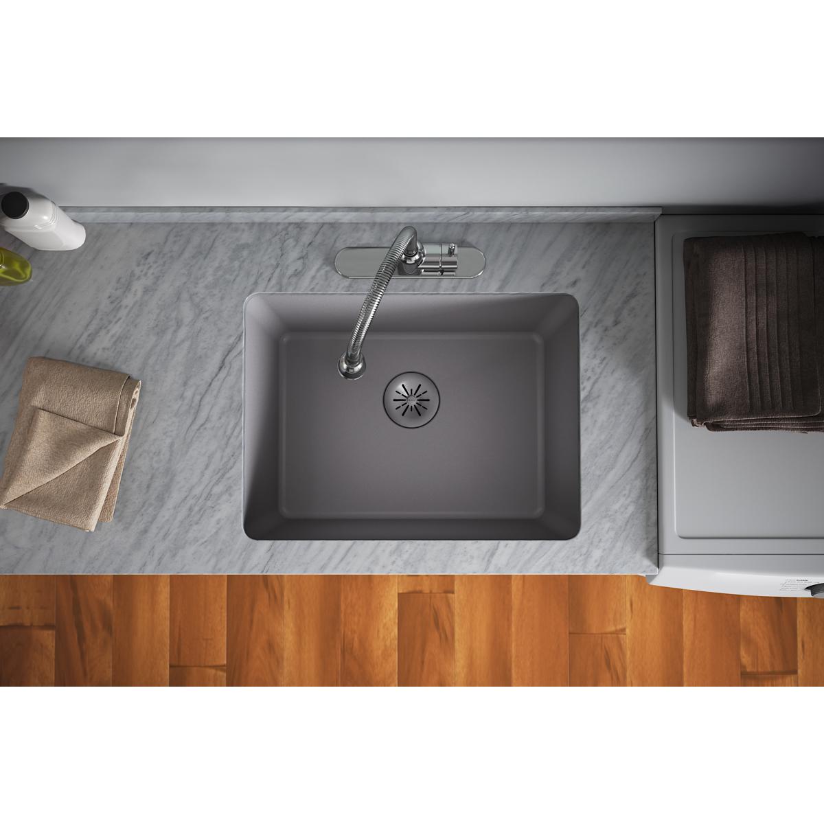 Greystone quartz sink with starburst drain strainer visible at bottom center and chrome faucet mounted above.