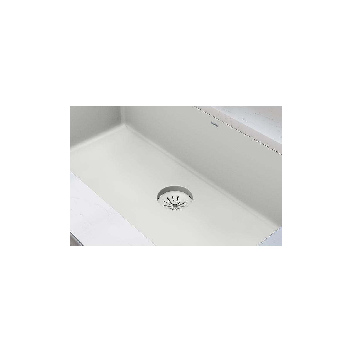 Parchment polymer basket strainer with gray rim installed in white quartz sink basin.