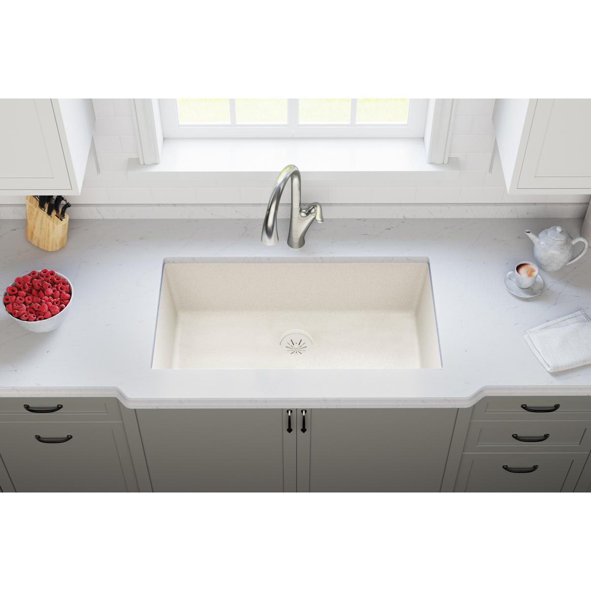 Parchment quartz undermount sink with drain strainer installed in white kitchen countertop.