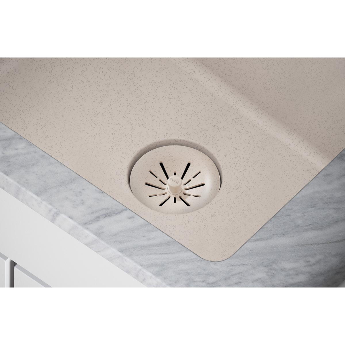 Beige quartz sink drain opening with removable polymer basket strainer basket visible in center.