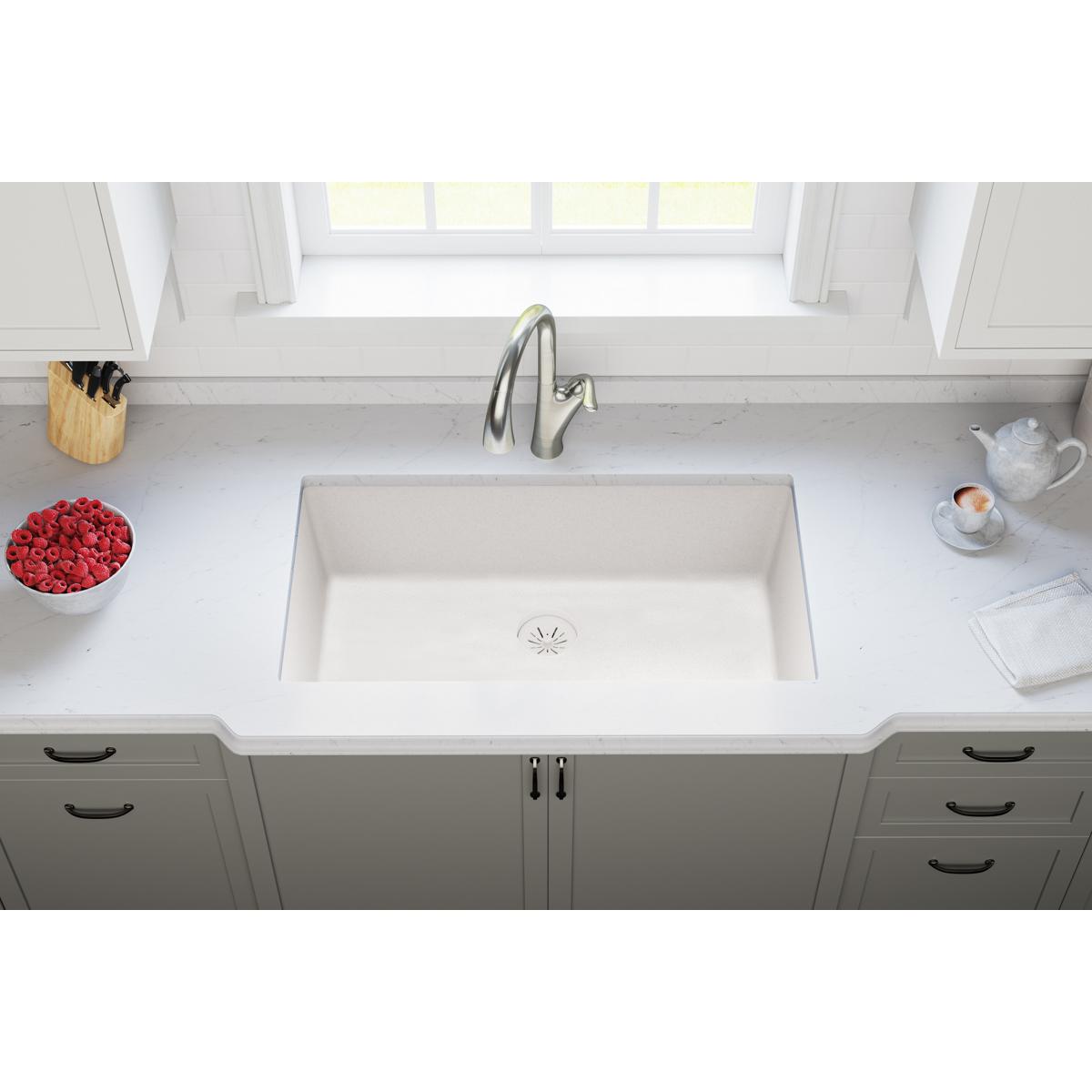 White quartz undermount kitchen sink with drain basket strainer visible at bottom center.