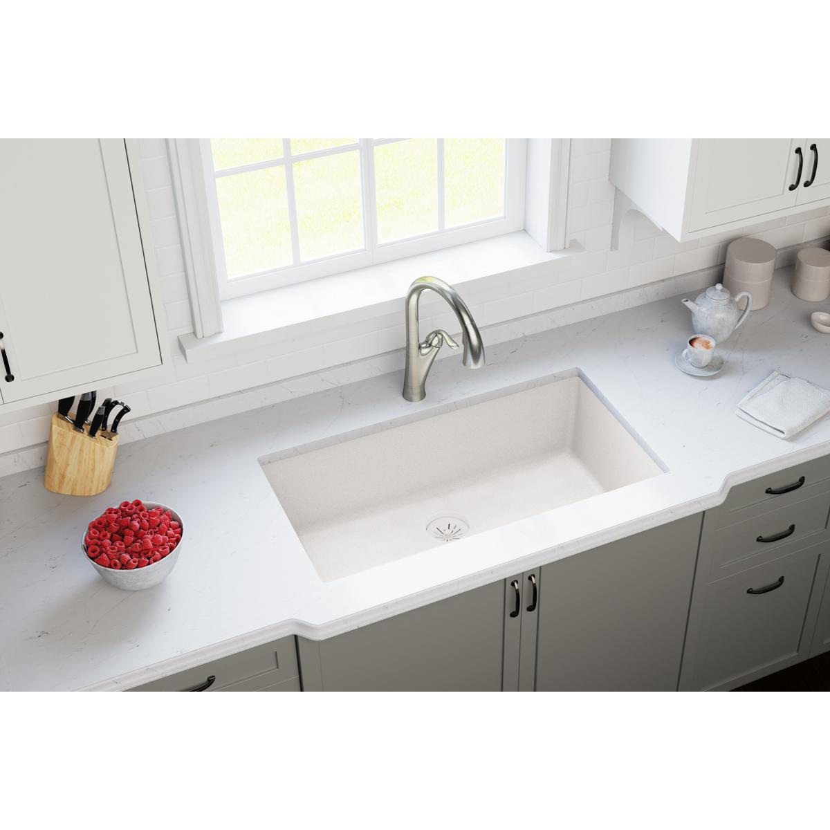White undermount kitchen sink with drain strainer visible in ricotta quartz countertop.