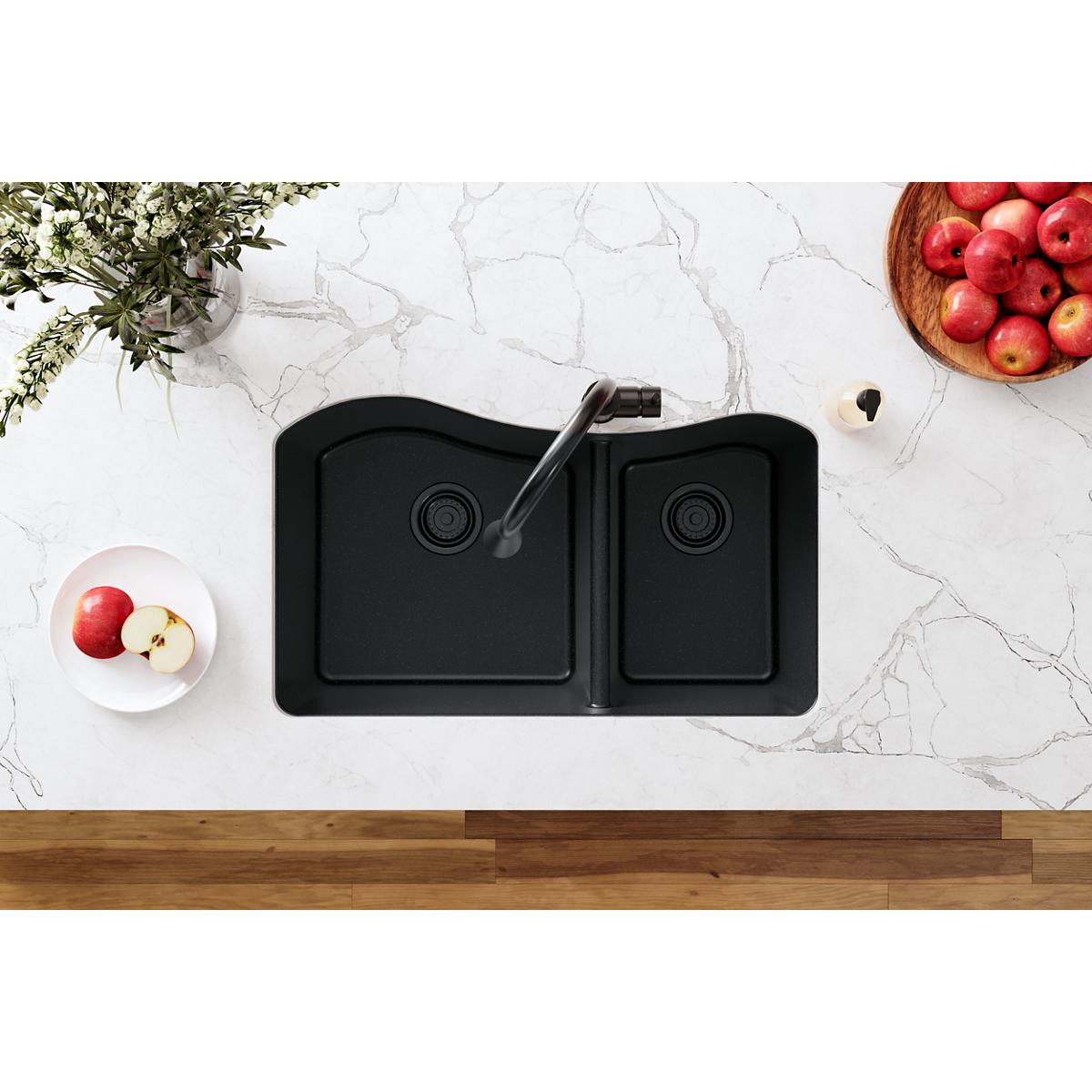 Black polymer double-bowl sink with faucet and basket strainer installed in white marble countertop.