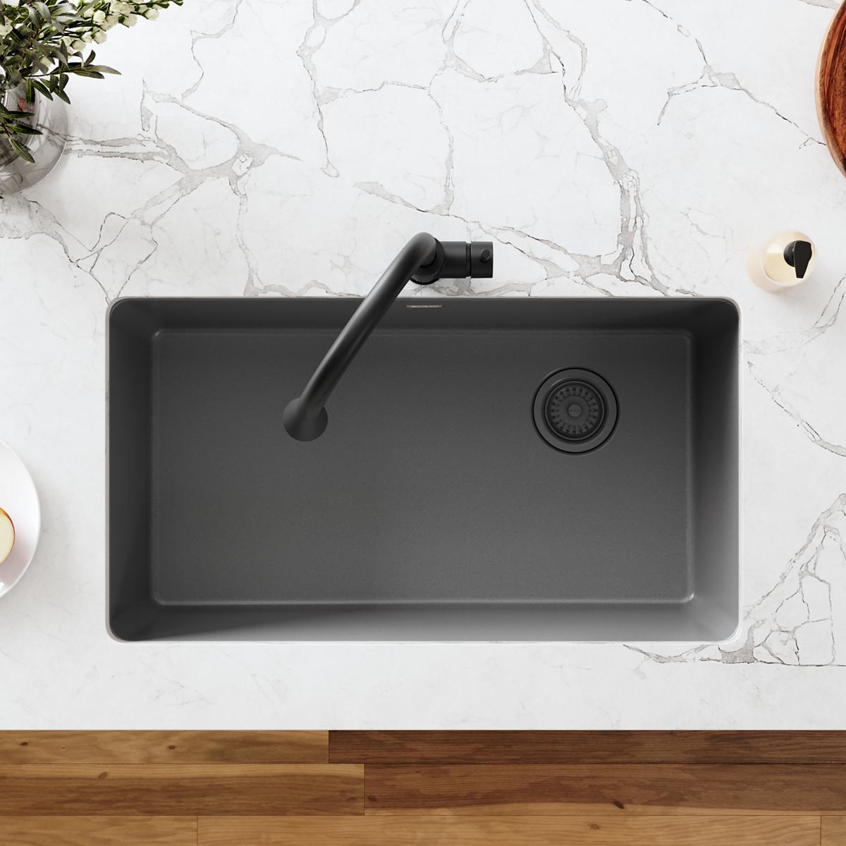 Dusk gray polymer sink with black curved faucet and circular drain basket strainer visible on right side.