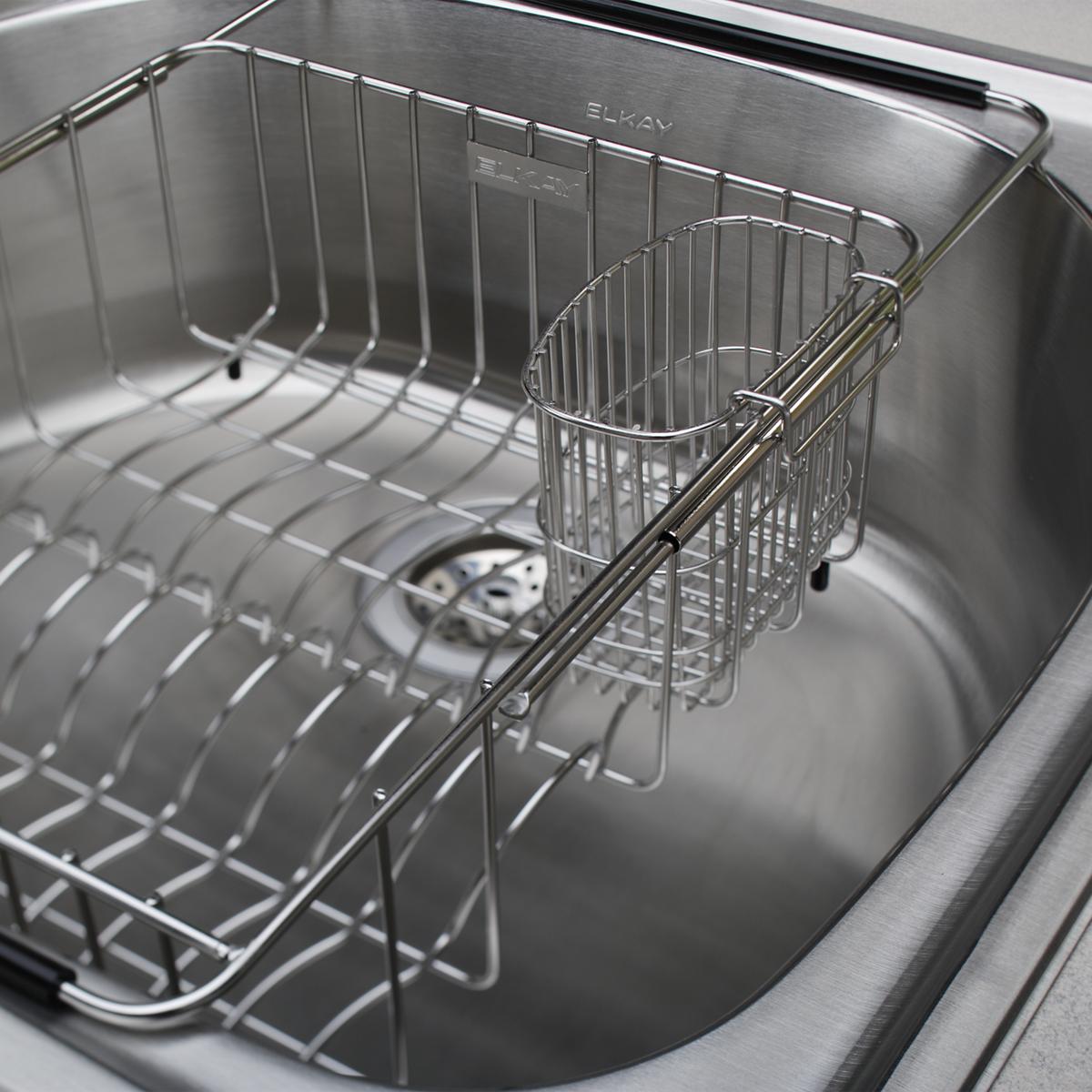 Stainless steel utensil caddy with wire construction mounted inside sink basin.