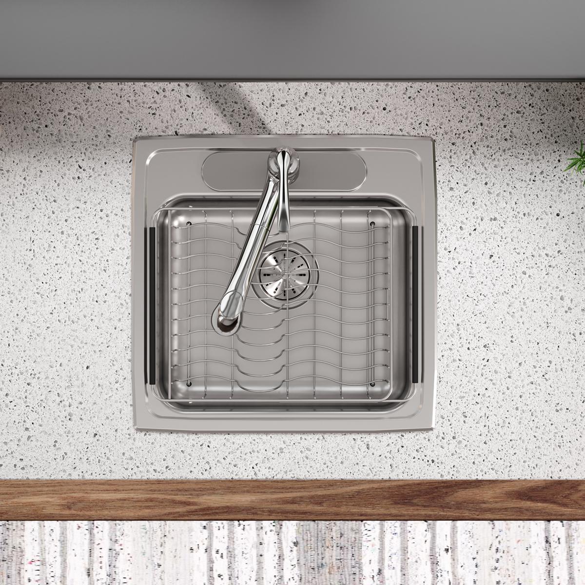 Stainless steel rinsing basket with grid pattern and handle, positioned in a sink.