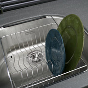 Stainless steel rinsing basket with wire grid design holding two plates inside a sink.