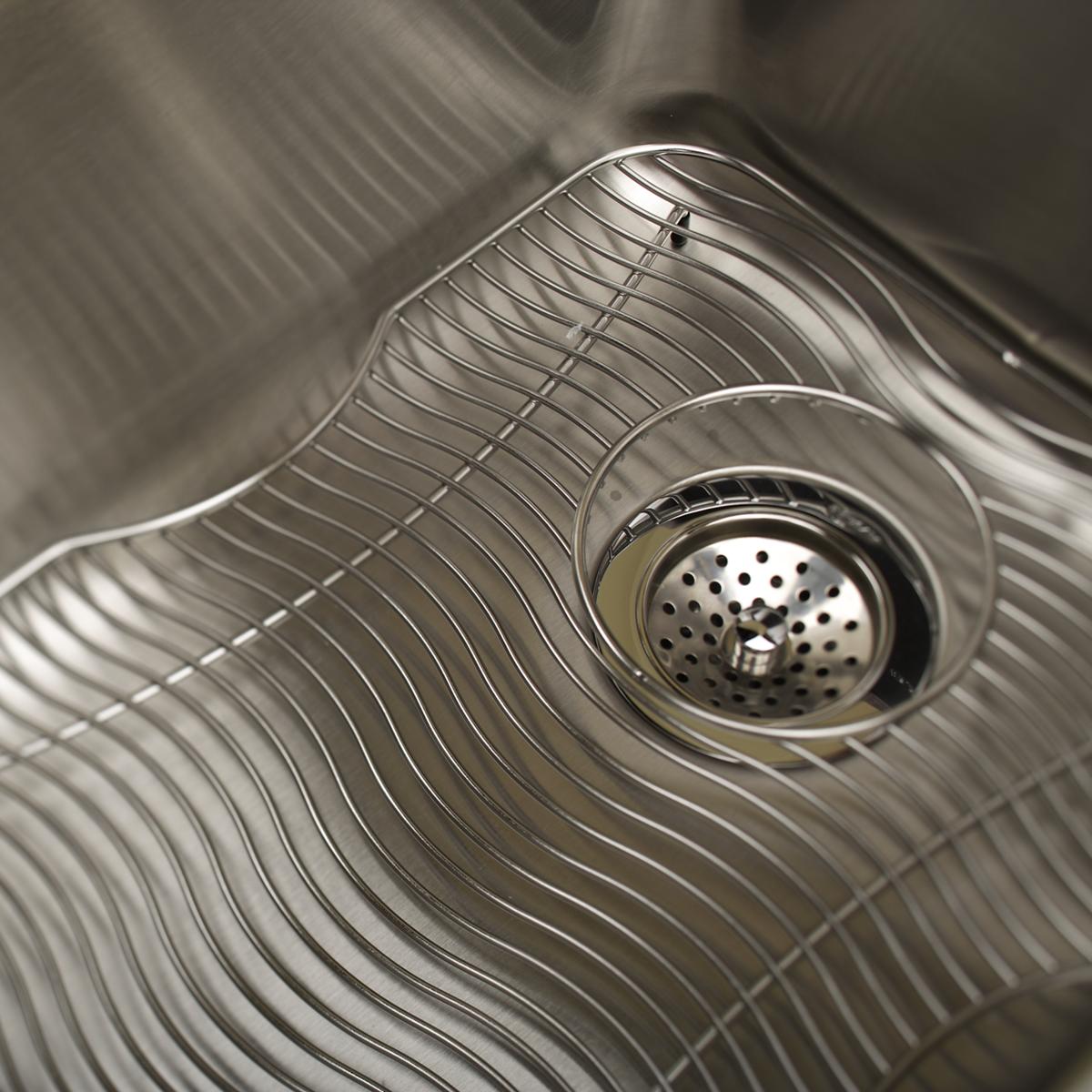 Stainless steel sink grid with parallel wire bars and strainer basket opening.