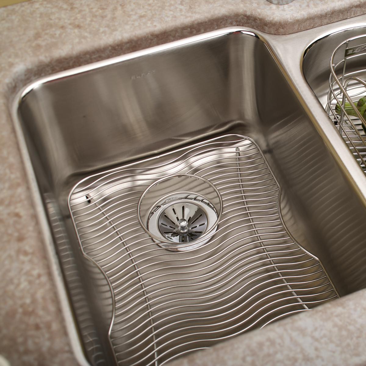 Stainless steel sink grid with parallel wire construction, fitted in kitchen sink basin.