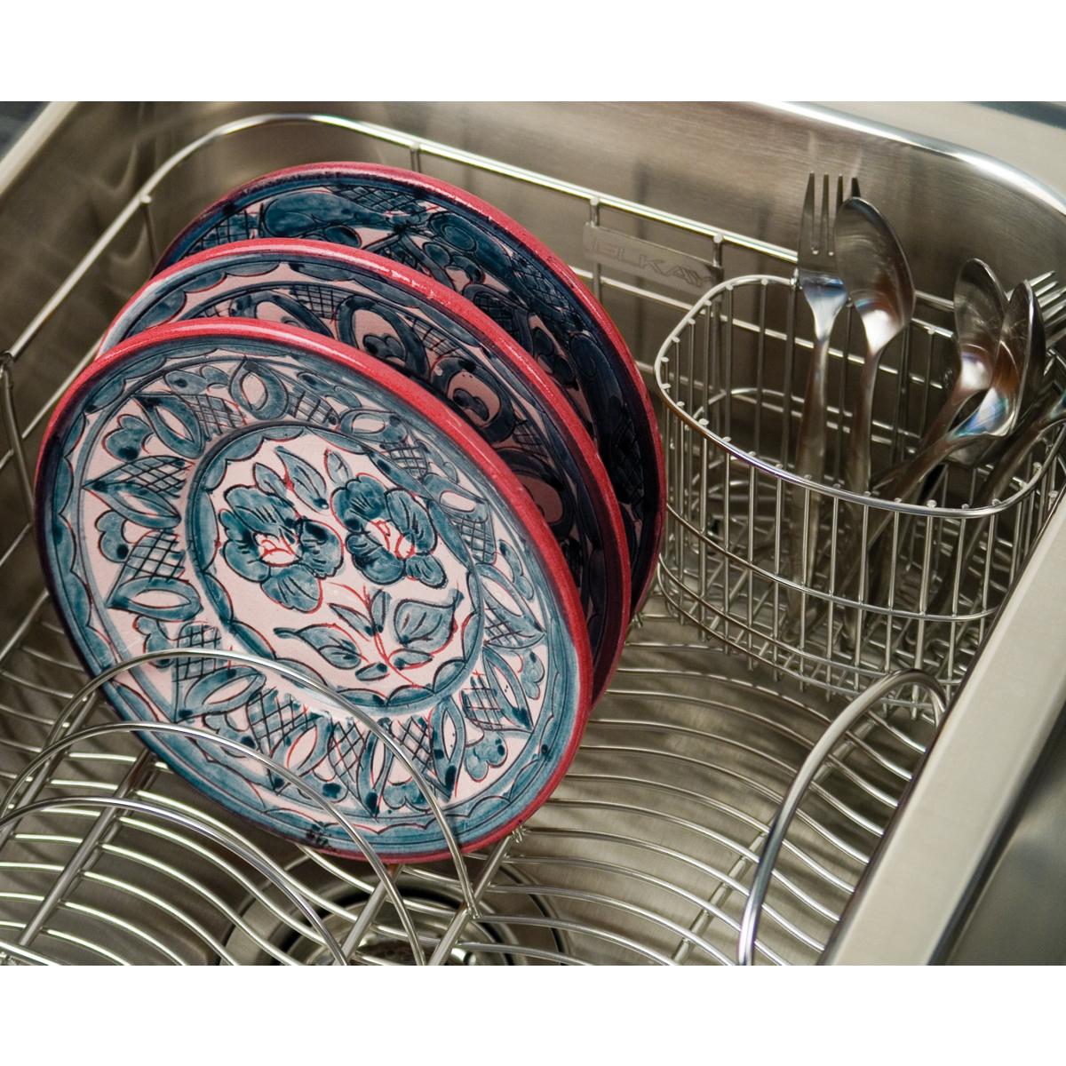 Stainless steel rinsing basket holding decorative plates with red rims and blue floral patterns in a sink.