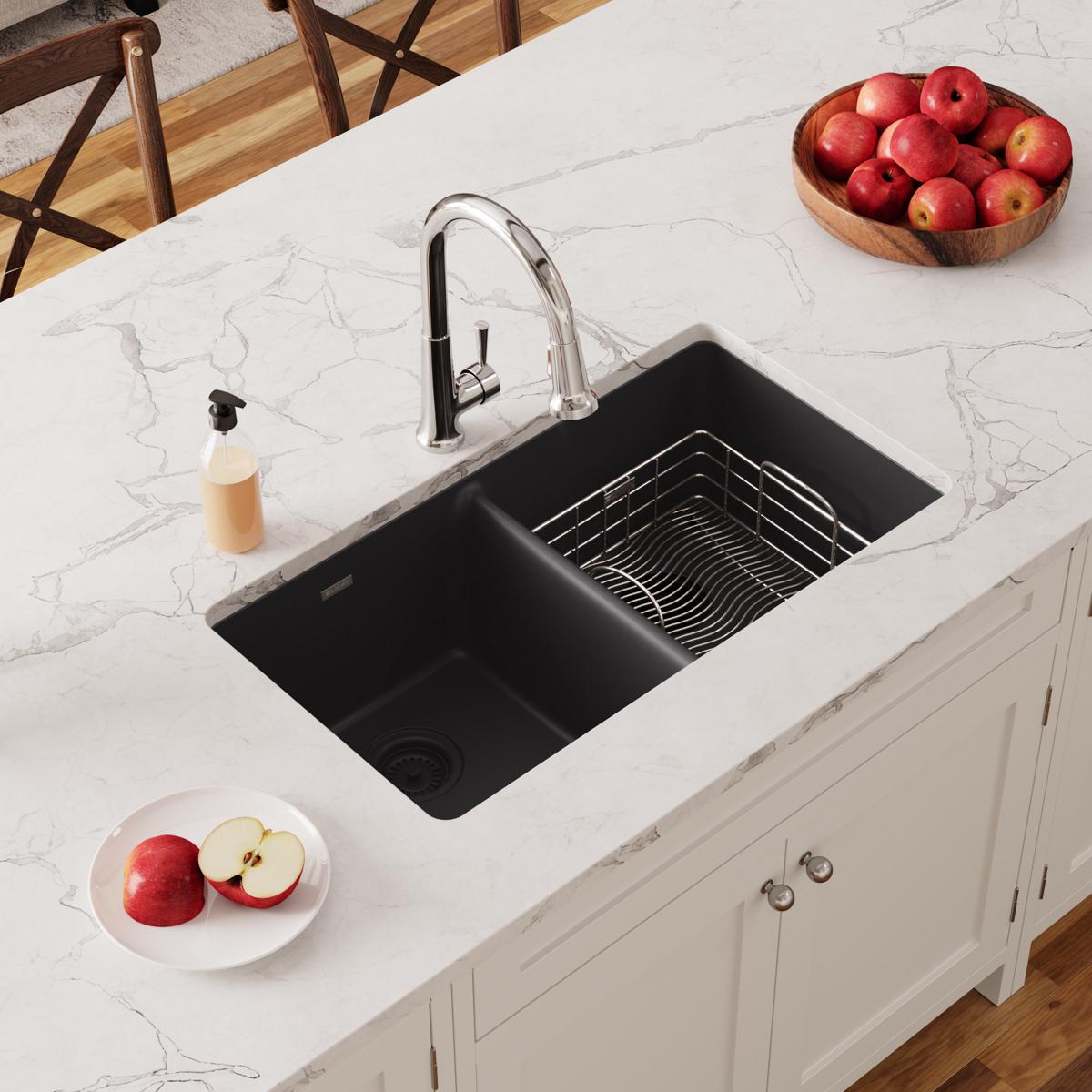 Stainless steel rinsing basket with parallel wire design sits inside black kitchen sink basin.