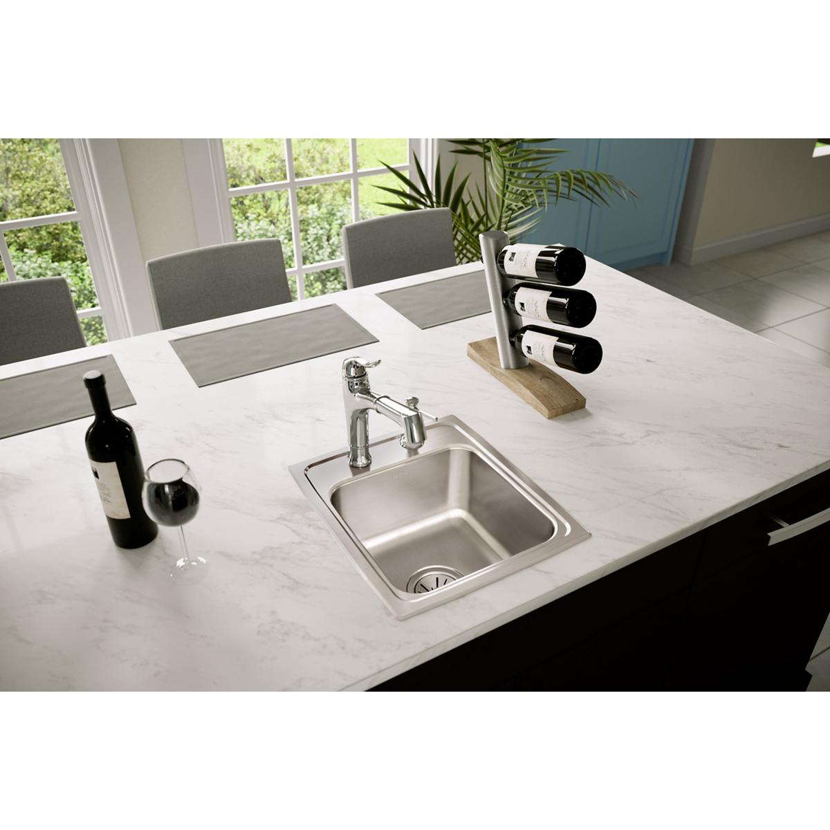 Stainless steel drop-in bar sink with single bowl and two faucet holes installed in white countertop.
