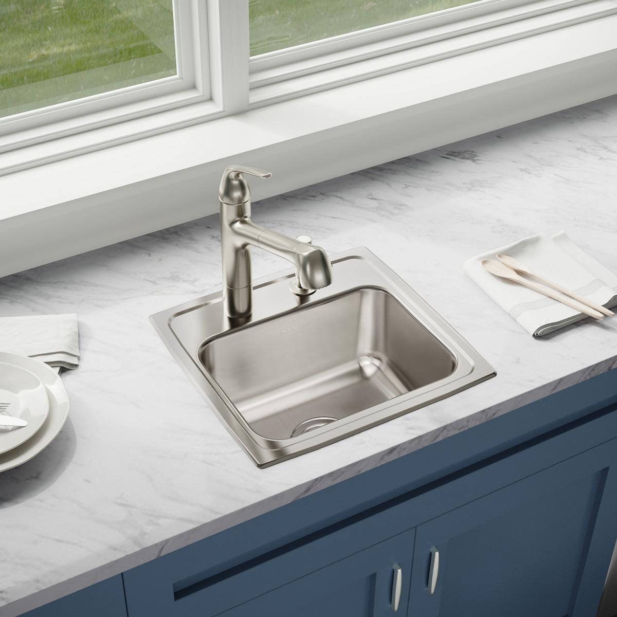 Stainless steel drop-in sink with single bowl and faucet installed in marble countertop.