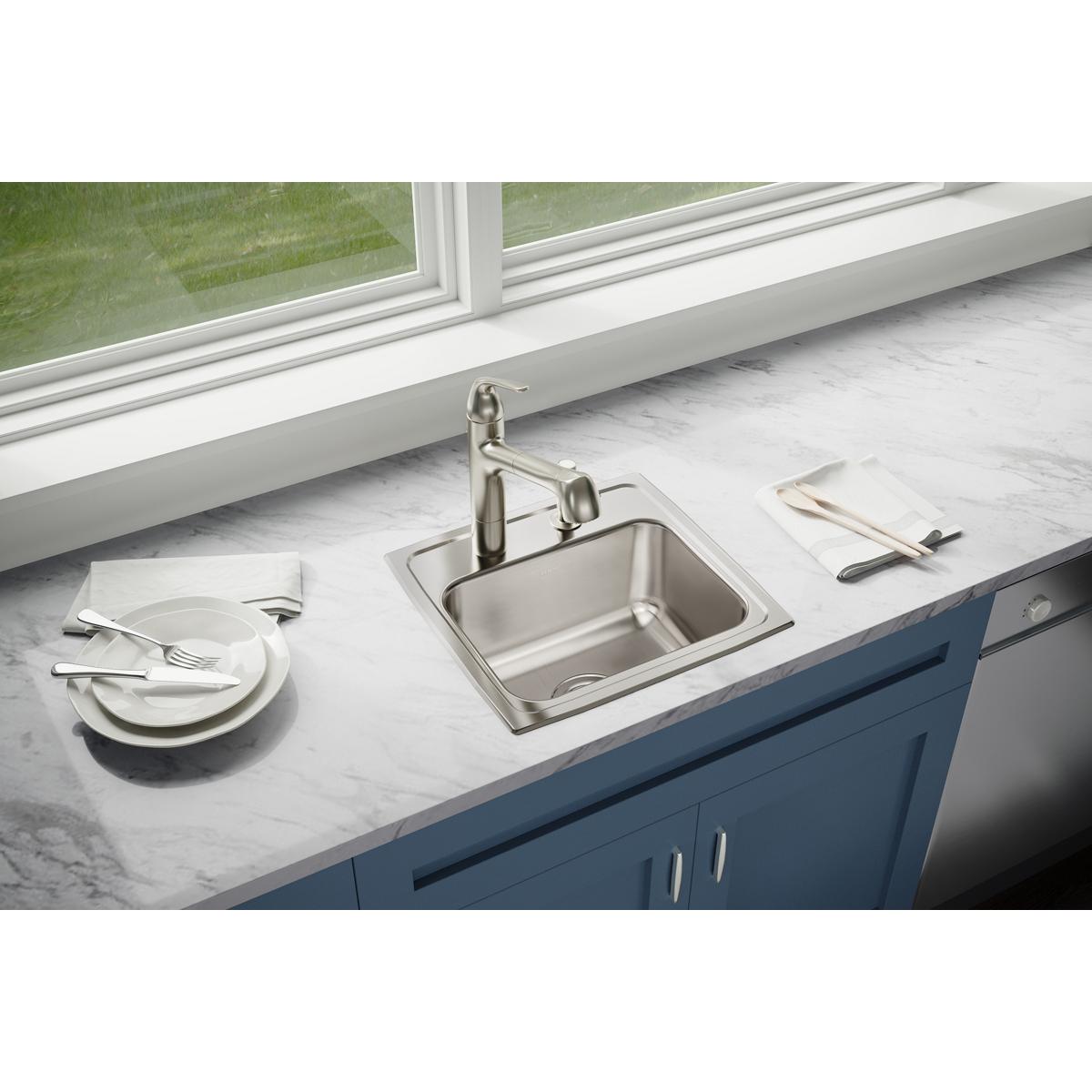 Stainless steel single bowl drop-in sink with faucet installed in white marble countertop above blue cabinet.