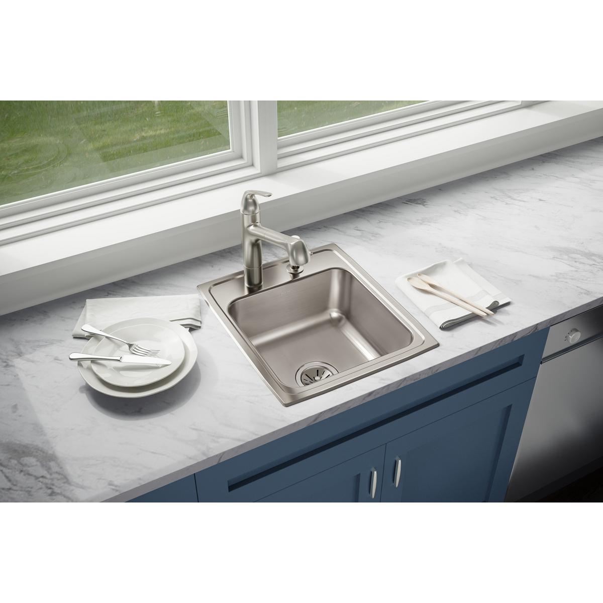 Stainless steel single bowl drop-in sink with three faucet holes installed in marble countertop with brushed nickel faucet.