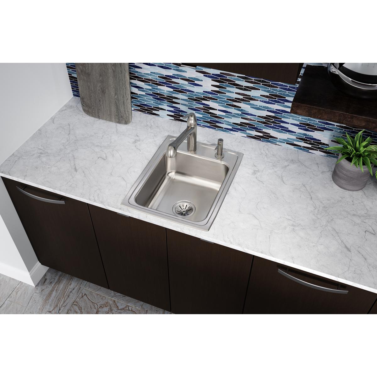 Stainless steel single bowl drop-in sink with three faucet holes installed in marble countertop.