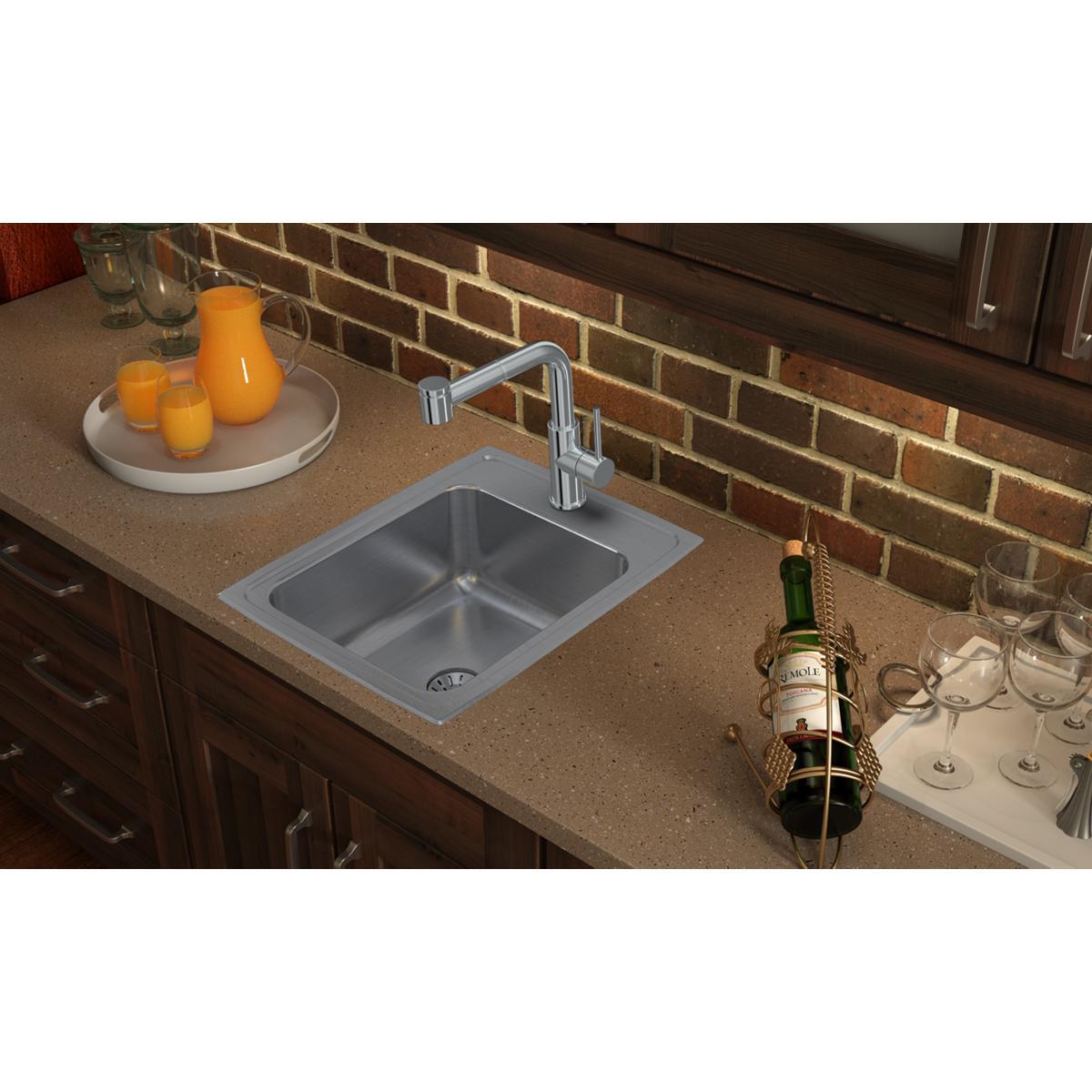 Stainless steel drop-in sink with single bowl and two faucet holes installed in countertop with chrome faucet.