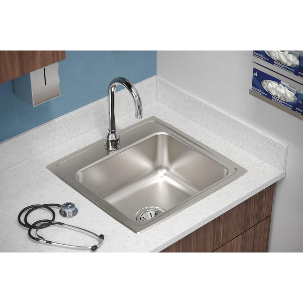 Stainless steel drop-in sink with single bowl, chrome faucet, and drain strainer on white countertop.