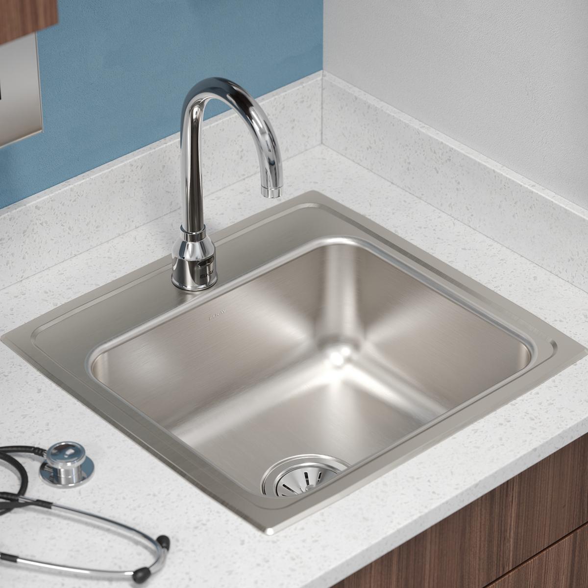 Square stainless steel drop-in sink with single bowl and one faucet hole, mounted in white countertop with chrome faucet.