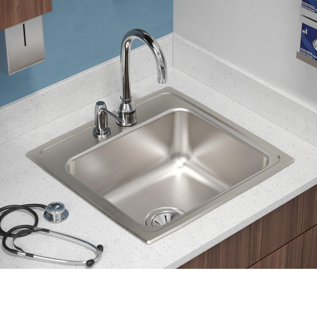 Stainless steel drop-in sink with single bowl, two faucet holes, and chrome faucet installed on white countertop.