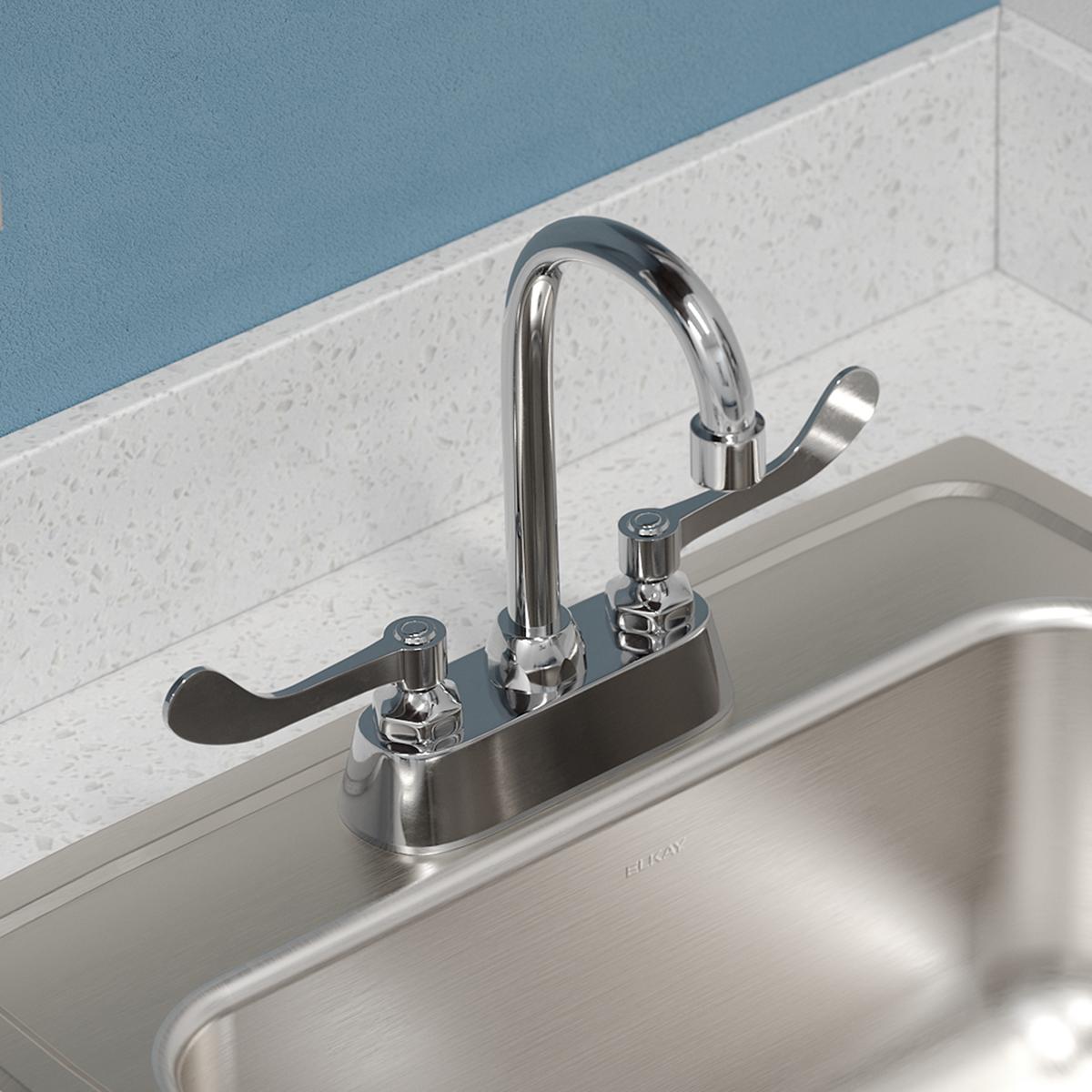 Stainless steel drop-in sink with brushed finish and chrome faucet with dual handles mounted on white countertop.