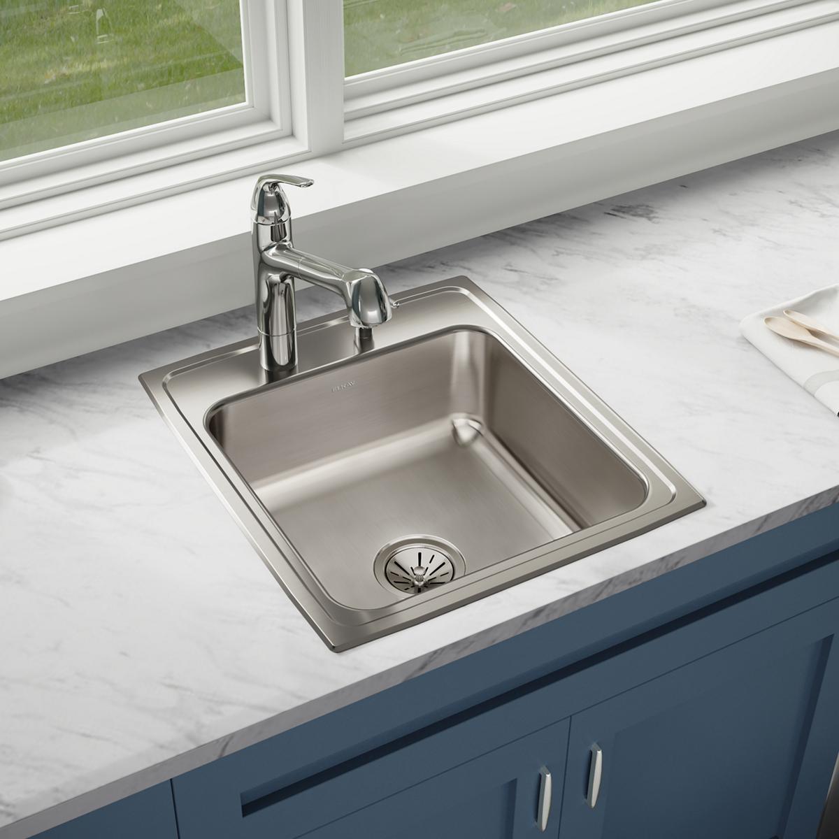 Stainless steel drop-in kitchen sink with single bowl and two faucet holes, installed in marble countertop with chrome faucet