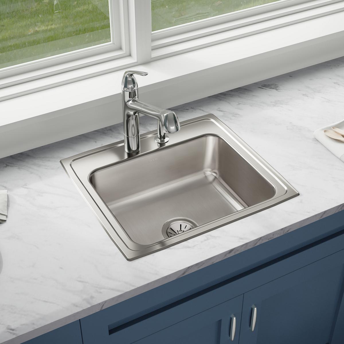 Stainless steel drop-in sink with single bowl, chrome faucet, and drain strainer installed in marble countertop.