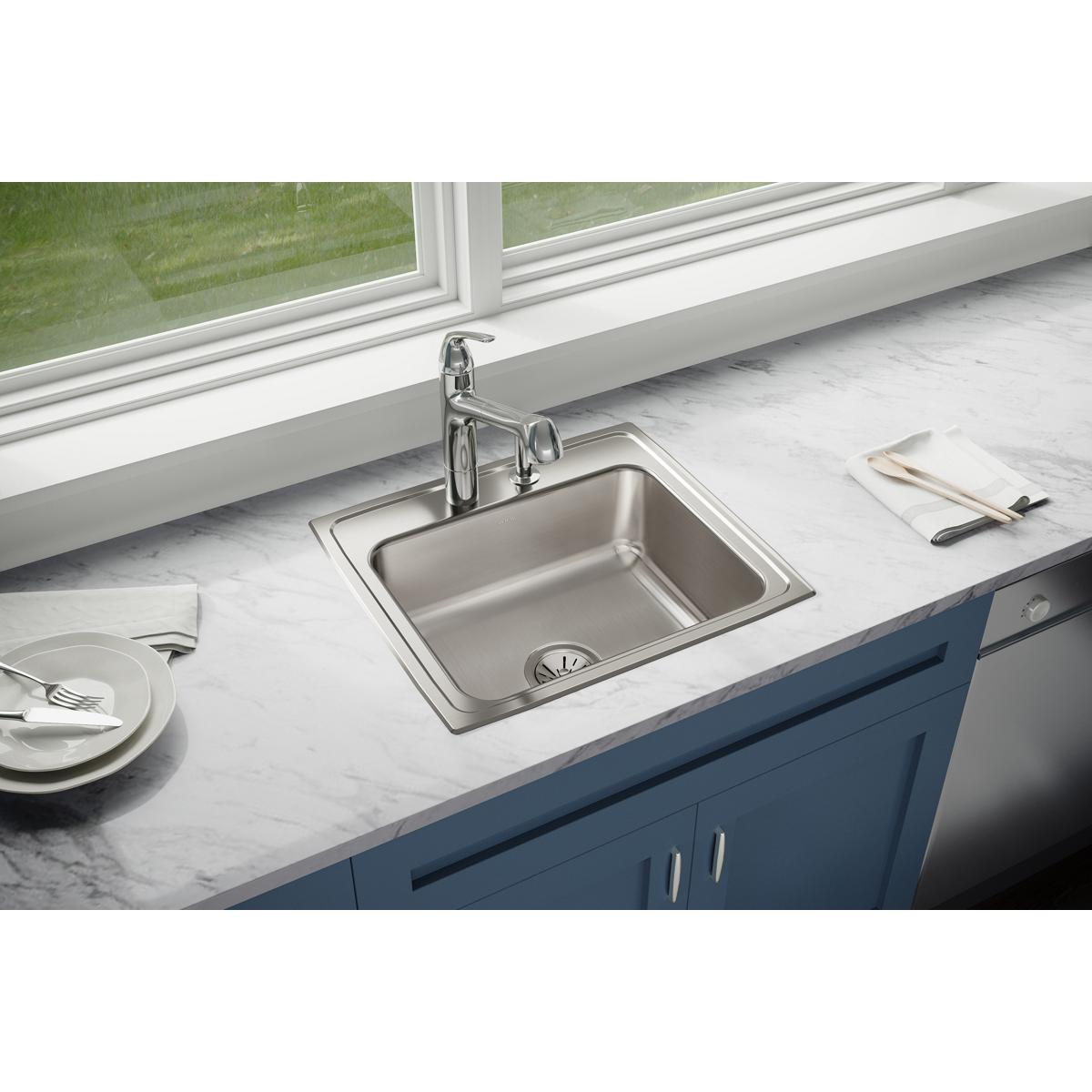 Stainless steel drop-in sink with single bowl and four mounting holes installed in white countertop with chrome faucet.